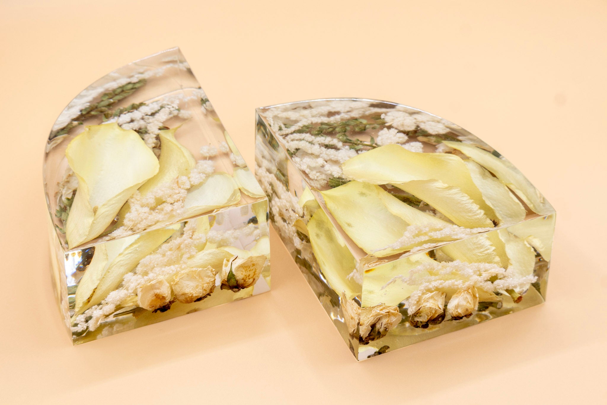 side view of two Clear resin bookends with dried white calla lily flower design on a beige background