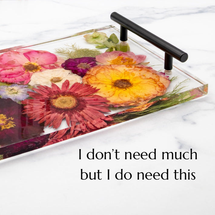 Resin serving tray with black handles preserving pressed roses, daisies and gerberas, displayed on a marble kitchen counter keepsake.