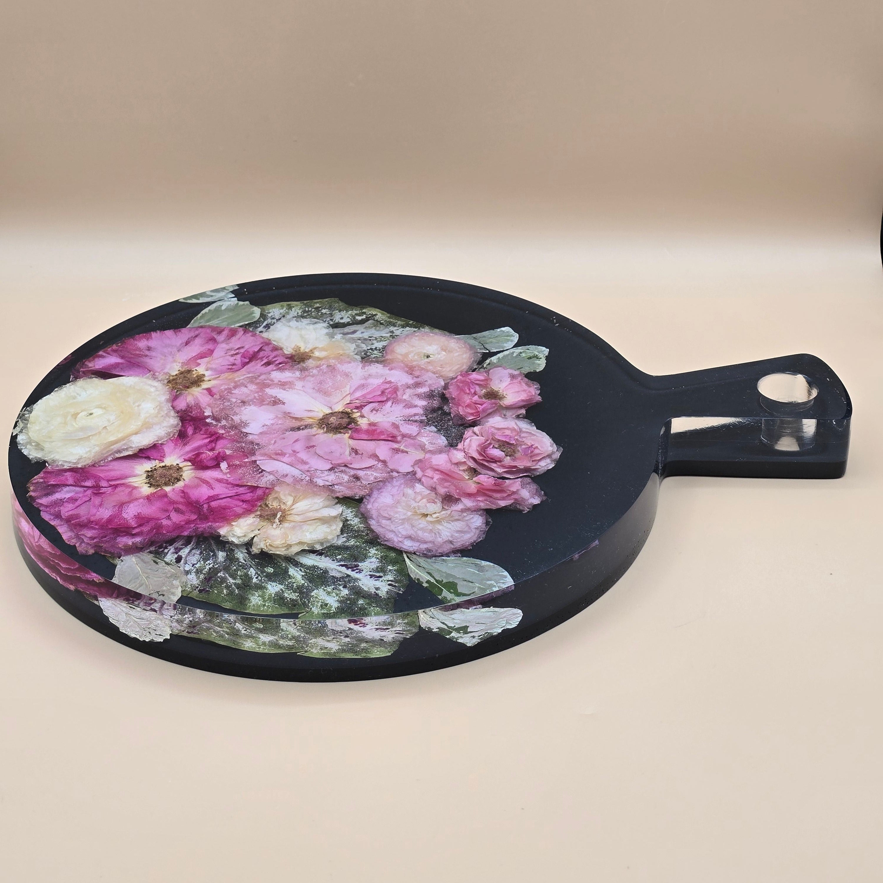 Side view Premade preserved flower charcuterie board with handle. Round serving board with pressed blooms in crystal-clear resin. Ready-to-ship floral gift.