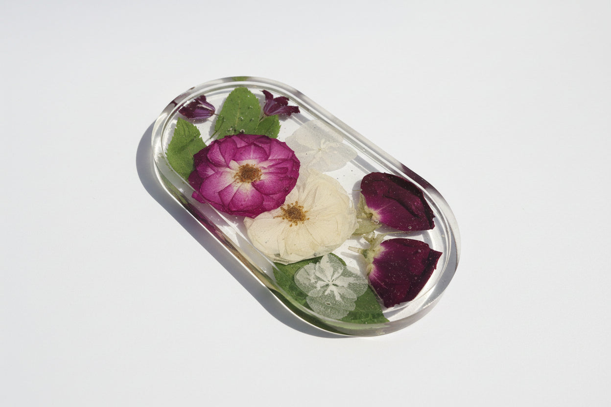 Small, oval-shaped resin dish with pressed flowers on a white background